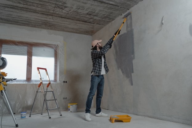 man painting wall with brush